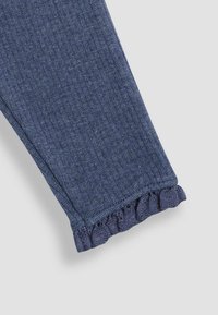 Denim leggings with a textured dark blue fabric. The hem features a ruffled design, adding a distinct detail to the leg openings.