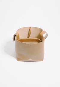 Borsa a secchiello in pelle naturale con texture liscia, design minimalista, manico superiore e scomparto interno. Presenta un logo del marchio sul davanti.