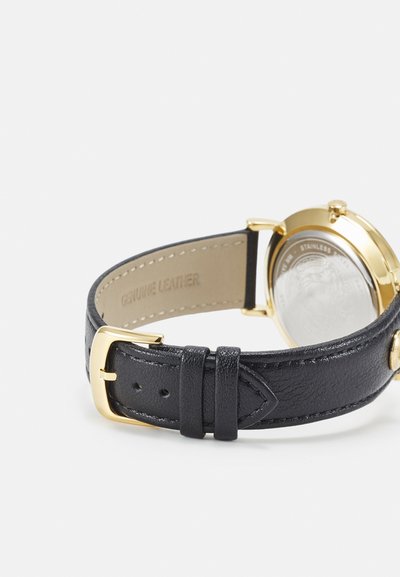 Black genuine leather watch strap with gold metal hardware, featuring a textured surface and smooth inner lining. Watch back is stainless steel.
