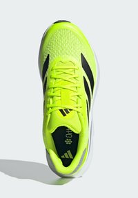 Athletic shoe in bright neon yellow mesh with black stripes. Features a patterned upper, padded collar, and textured sole for traction.