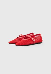 Ballerines en maille rouge à bout pointu, avec une sangle décorative et une boucle argentée, montées sur une semelle noire plate.