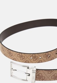 Ceinture marron à motif avec un tissu beige, dotée d'une boucle en métal argenté et de plusieurs trous de réglage sur le bord.