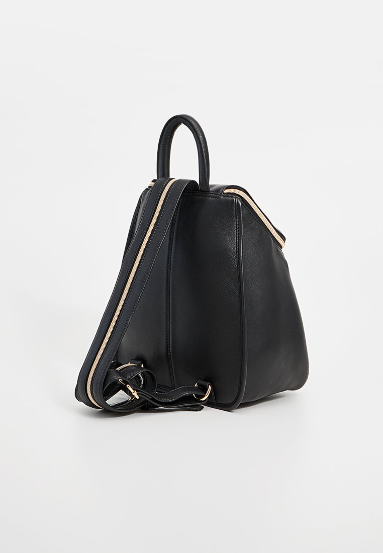 Sac à dos en cuir noir de forme arrondie, avec des accents de fermeture éclair dorés et deux poignées. Comprend une bandoulière amovible pour une utilisation polyvalente.