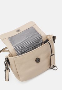 Beige läderväska med en strukturerad yta, med ett randigt svart och vitt foder och en tryckknappsstängning. Inkluderar en avtagbar rem.