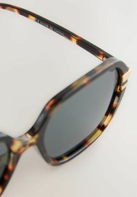 Sonnenbrille mit Schildpatt-Muster, dunklen Gläsern, rechteckiger Form, dicken Acetatgestellen und einem metallischen Akzent an den Bügeln.