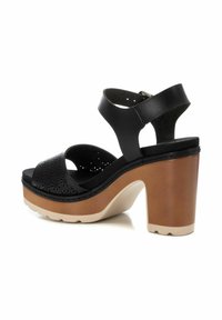 Sandalias de plataforma de cuero negro con detalles perforados, cintas anchas, punta abierta y un tacón grueso marrón. Suela texturizada para una mayor estabilidad y agarre.