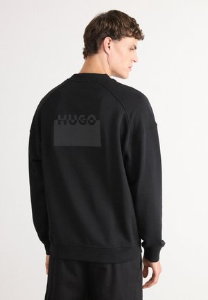 Black sweatshirt with a textured logo at the back. Features a ribbed collar and cuffs, and a relaxed fit. Soft fabric with a smooth texture.