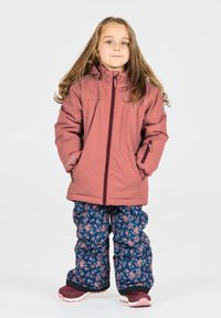 Rosa isolierte Jacke mit einem vorderen Reißverschluss, kombiniert mit navyblauen Schneehosen mit floralem Muster. Beide Teile haben einen entspannten Schnitt und eine warme Textur.