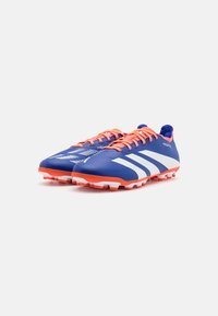 Botas de fútbol azules con acentos naranjas, que presentan un material texturizado, rayas blancas, y una suela moldeada con tachuelas de tracción.
