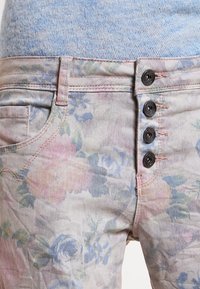 Blommiga jeans i denim med en mjuk, pastellfärgad design med rosa och blå rosor. Femknapps framknäppning och lätt textur.