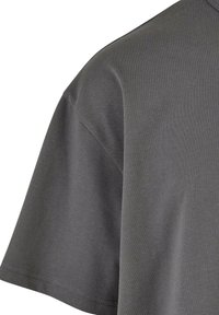 T-shirt en coton gris foncé à manches courtes avec des coutures visibles sur l'ourlet des manches et la couture de l'épaule.