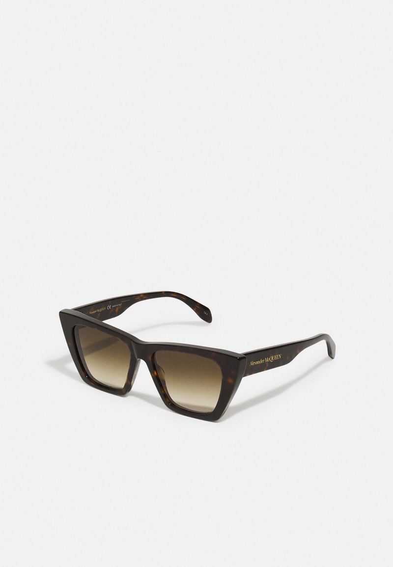 Brown tortoiseshell sunglasses with a geometric frame, gradient lenses, and gold logo detailing on the arms.