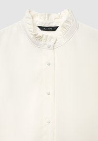 Weiße Bluse mit Knopfleiste und Rüschkragen, mit glatter Textur und kleinen Knöpfen. Das Etikett trägt die Aufschrift "CALLIOPE", Größe S.