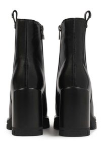 Botines de cuero negro con una textura suave, que cuentan con un tacón cuadrado, cierre con cremallera y una lengüeta en la parte trasera para facilitar su puesta.