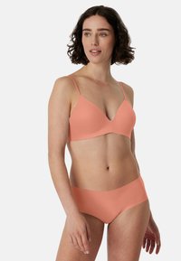 Peachfarvet bh og matchende trusse med tynde stropper. Stoffet er glat og sømløst, og designet er støttende.