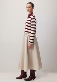 Pruhovaný kardigan v burgundské barvě a bílé, přes beige vzdušnou sukni; doplněn burgundskými vysokými botami, hladký povrch a přiléhavý silueta.