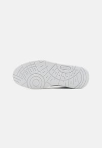 Hvitt gummisåle til sneakers med en teksturert, mønstret design; har merkevarelogo og sirkulære detaljer. Flat, sklisikker overflate.