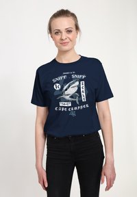 Námořnická modrá tričko s krátkým rukávem, které obsahuje grafiku žraloka, textové prvky a vtipný design s bílými akcenty.