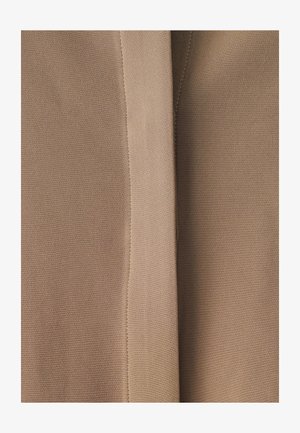 Beige stof met een gladde textuur, met gestikte naden en subtiele variaties in tint, gevouwen om zijn zachte val te tonen.