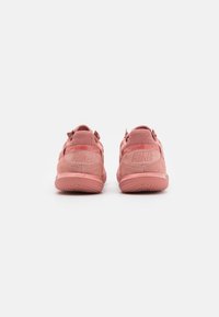 Buty Nike w miękkim różowym zamszu z siateczkowymi akcentami, z teksturowanymi podeszwami, wytłoczonym logo na pięcie i pętlami z tyłu.