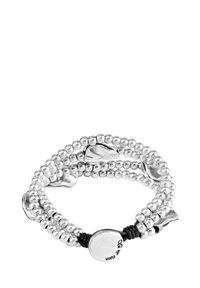 Pulsera elástica de plata con múltiples cadenas de cuentas de metal y acentos suaves de forma irregular; presenta una etiqueta de logo central.