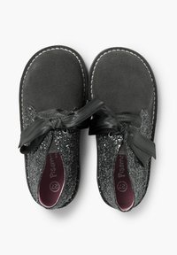 Zapatos de ante negro con una parte superior brillante en negro, que presentan un gran lazo de satén negro, plantillas rosas y costuras blancas en contraste en los bordes.