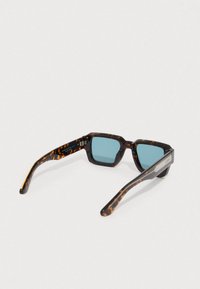 Sončna očala iz želvjevega vzorca z modrimi lečami, pravokotnim okvirjem in teksturiranimi ročaji s srebrnim poudarkom.