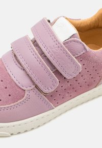 Sneaker in pelle e camoscio viola con due cinturini in velcro, design perforato e suola in gomma bianca. L'interno presenta un rivestimento beige chiaro.