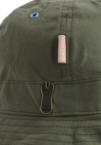 Πράσινο καπέλο τύπου bucket με μπλε αεραγωγό, μπεζ υφασμάτινη ετικέτα και μαύρο καρφί τσέπης σε σχήμα καστάνιας με τη φράση Paul Smith Barbour.