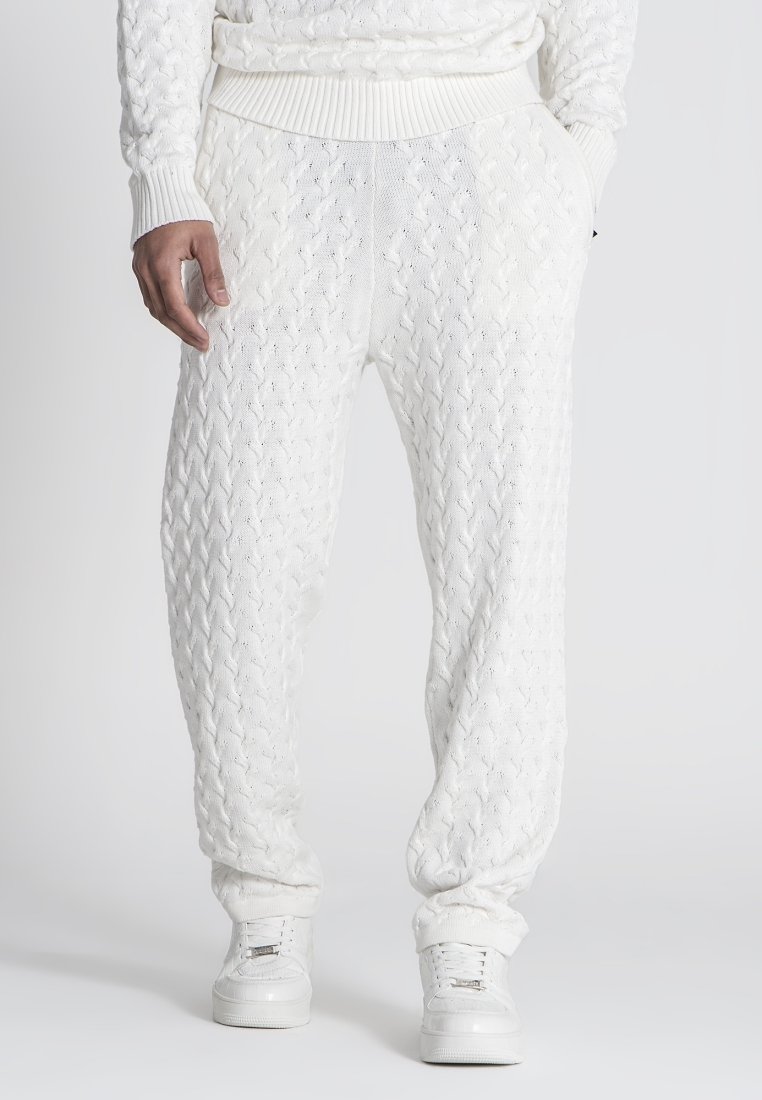 Witte gebreide joggingsbroek met een gestructureerd kabelpatroon, geribbelde tailleband en boorden. Gepaard met witte sneakers.