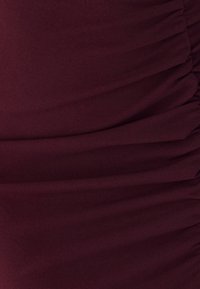 Burgundia veniv materjal, millel on kogutud tekstuur, peened vertikaalsed jooned ja pehme, sile pind. Pole nähtavat riistvara ega aktsente.