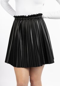 Gonna nera a pieghe in materiale sintetico, con vita arricciata e fondo svasato, che mette in risalto una texture liscia e un design strutturato.