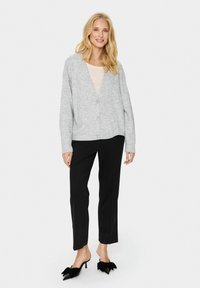 Hallux hallitus hõbeirohke sobiv riie, millel on V-kaelus, nööbid ja soonikkoes varrukad, koos mustade pükstega ja mustade kandiliste madudega, millel on paelade aktsent.