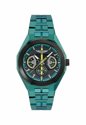 Reloj metálico color azul verdoso con caja octagonal, esfera negra, acentos en amarillo y blanco, tres subesferas y una pulsera metálica integrada.