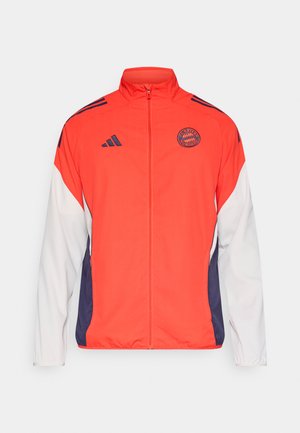 Red and white athletic jacket featuring a high collar, full zip, and navy blue accents. Includes a circular logo on the chest and three stripes on the shoulders.