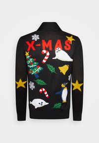 Svart stickad tröja med färgglada julmotiv: ett träd, sälar, en pingvin, godiskäppar, snöflingor och mistel. Texten lyder "X-MAS."