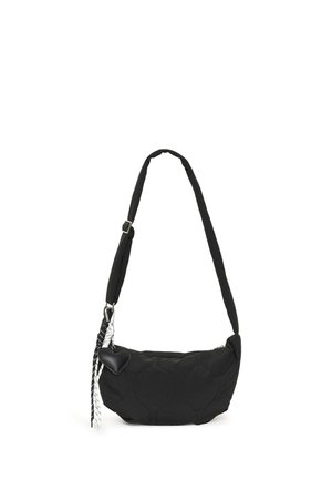 Black quilted shoulder bag with adjustable strap, heart-shaped charm, and black-and-white tassel hanging on one side.