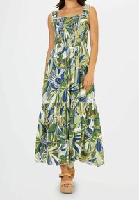 Robe longue avec corsage froncé, imprimé de feuilles vertes et bleues, et jupe à volants à étages. Confectionnée en tissu léger avec bretelles ajustables.