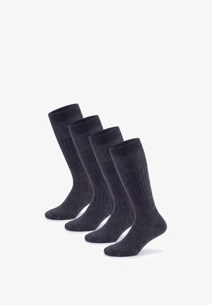 Vier Paare schwarzer, gerippter knielanger Socken, diagonal auf weißem Hintergrund angeordnet.
