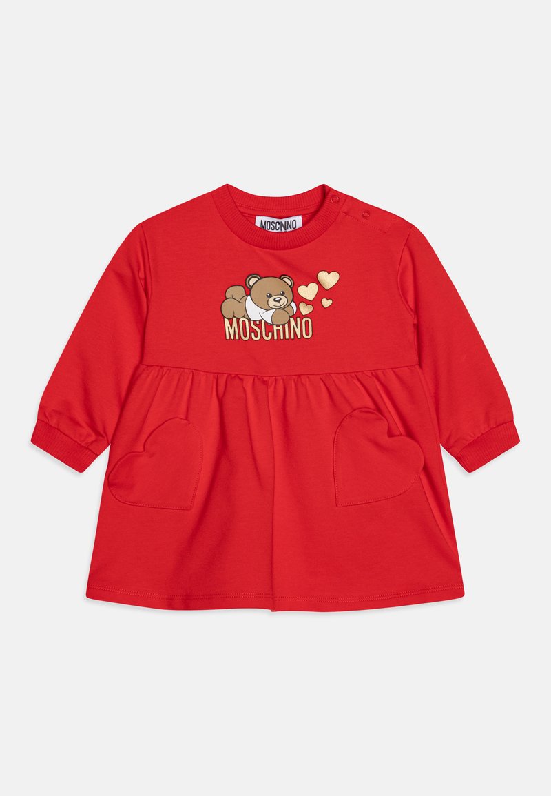 Rdeča bombažna obleka z dolgimi rokavi, ki ima potisk medvedka, žepke v obliki srca in zlate poudarke. Blagovna znamka: Moschino.
