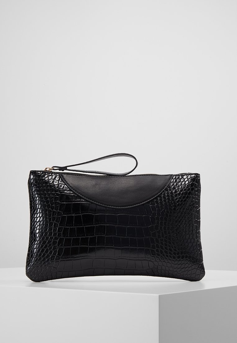 Pochette noire à bracelet avec texture crocodile et garniture en cuir lisse, exposée sur un piédestal blanc sur fond gris uni.