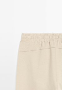 Beige sweatpants met een elastische tailleband, een gladde textuur en een eenvoudig ontwerp. Geen zichtbare patronen of hardwaredetails.