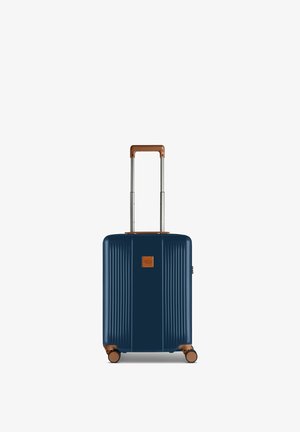 Valigia rigida blu navy con manico e bordatura marroni, quattro ruote e manico telescopico esteso.