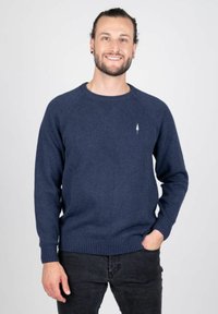 Pull bleu marine en tricot lisse avec un col rond côtel�é et un ourlet, présentant un emblème d'arbre blanc sur la poitrine gauche.