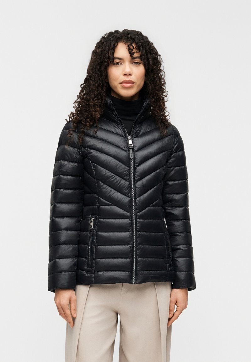 Μαύρο μπουφάν τύπου puffer με ραφές σε σχέδιο Chevron, ψηλό γιακά, κλείσιμο με φερμουάρ και δύο πλαϊνές τσέπες. Κατασκευασμένο από ελαφρύ, γυαλιστερό υλικό.