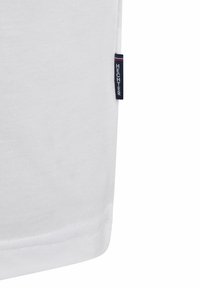 Tissu blanc avec une finition texturée, présentant une étiquette bleu marine portant la mention "HECHTER" avec des rayures rouges et blanches sur le bord.