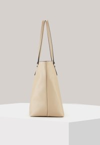 Beige læder tote taske med en struktureret overflade, der har to slanke stropper og en struktureret, vinkelret form.