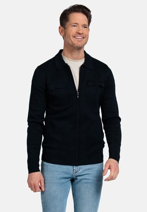 Zwarte gebreide zip-up jack met een kraag, twee borstzakken en geribde manchetten. Draag het over een lichtbeige shirt en in combinatie met blauwe jeans.