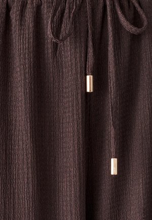 Brūna teksturēta auduma bikses ar elastīgu jostu un saites auklu, kuras izceļ zelta akcenti uz saites galiem.