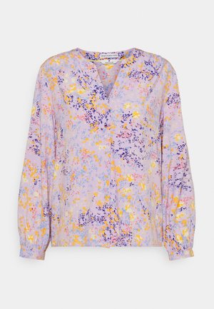 Blouse mauve clair à manches longues avec col en V et motif floral jaune, rose, bleu et violet foncé.